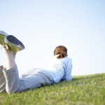 Young Woman Lying on Stomach on Grass